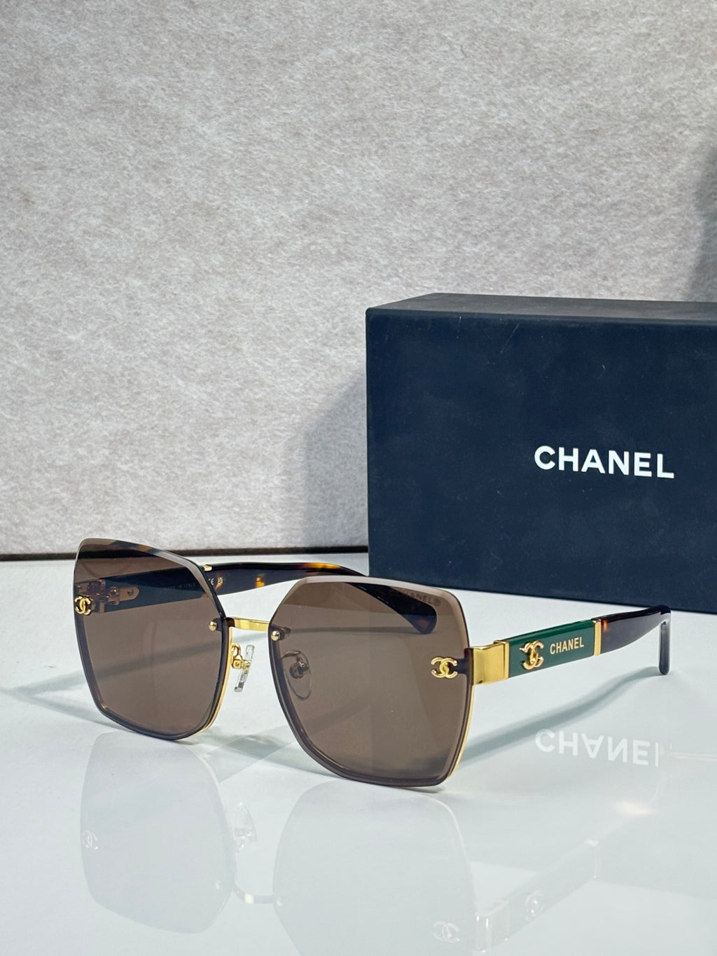 Chanel sunglasses with dark brown gradient lenses and gold-tone frame, CHANEL logo on temple