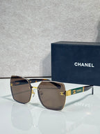 Chanel sunglasses with dark brown gradient lenses and gold-tone frame, CHANEL logo on temple