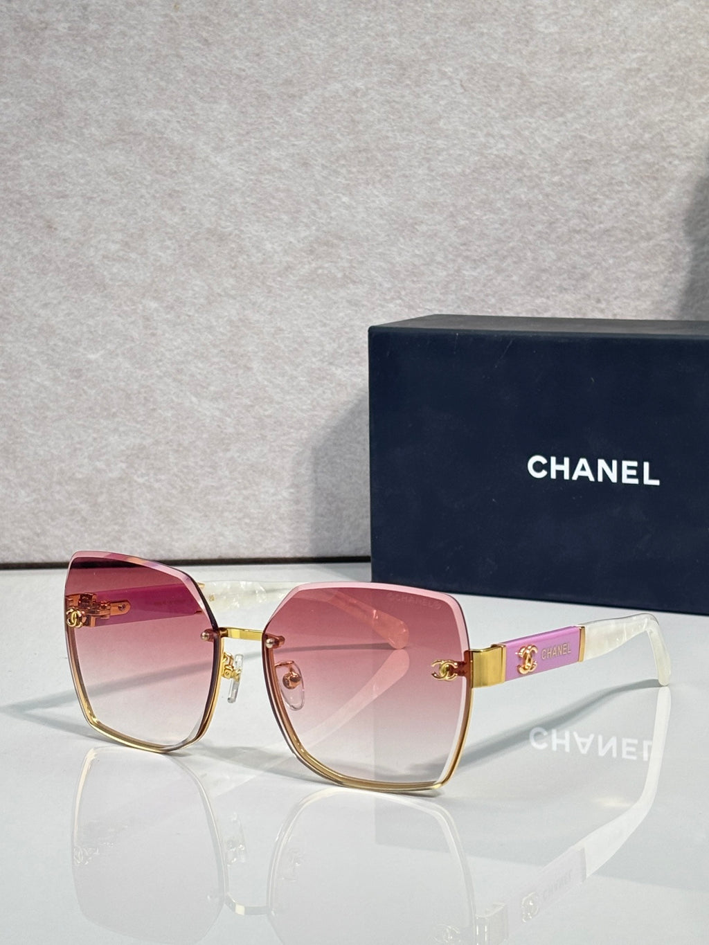 Chanel sunglasses with pink gradient lenses and gold-tone frame, logo hardware on temples