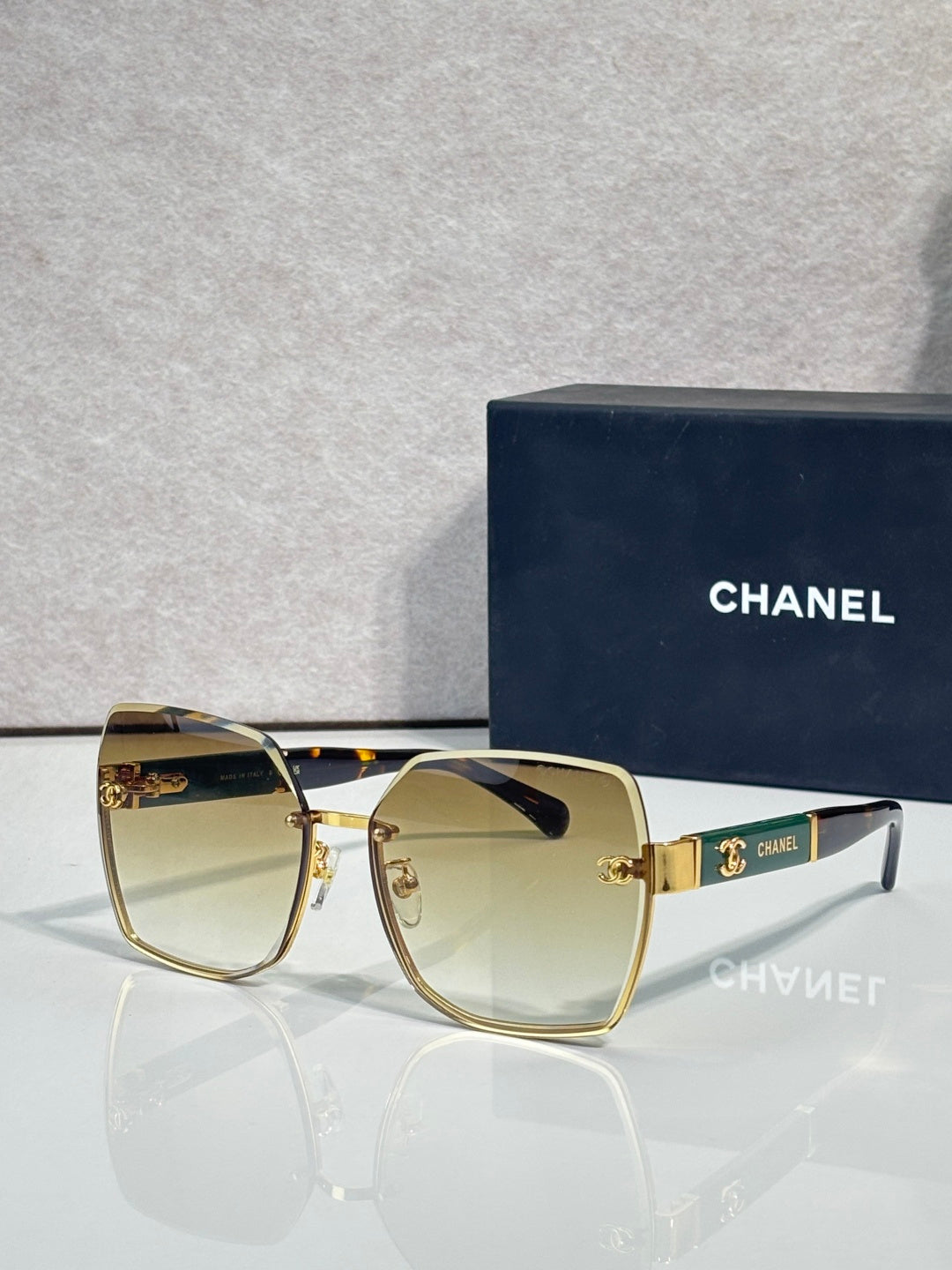 Chanel sunglasses with amber gradient lenses and gold-tone frame, logo hardware at temple