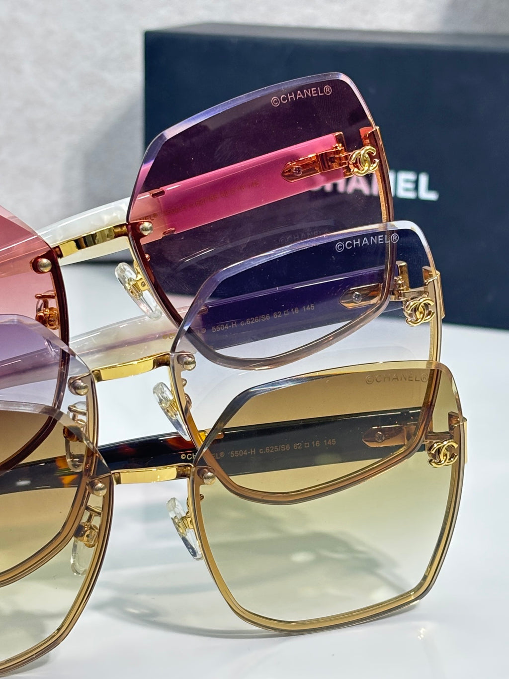 Chanel sunglasses close-up with purple and clear lenses, gold-tone frame and side logos