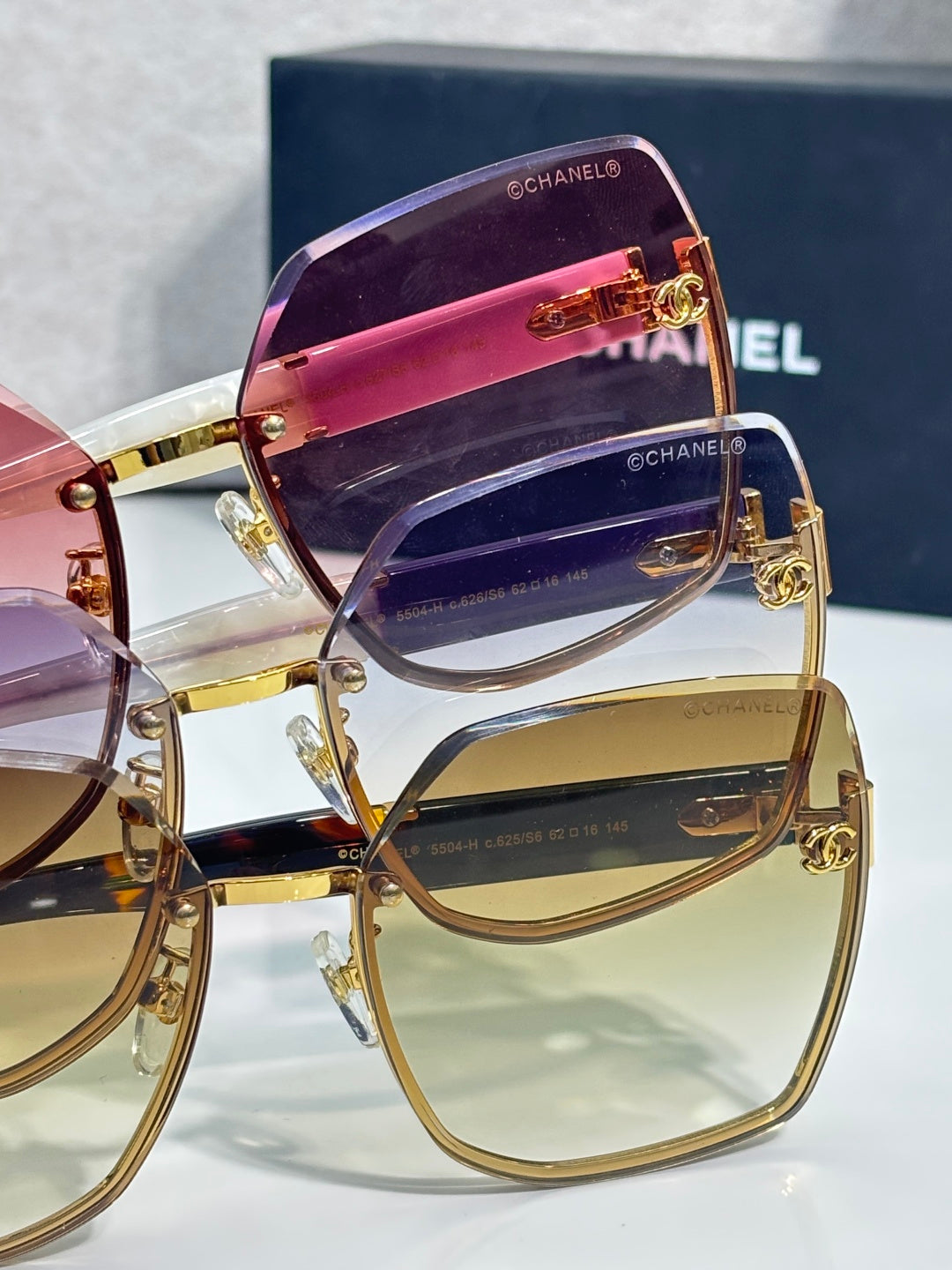 Chanel sunglasses close-up with purple and clear lenses, gold-tone frame and side logos