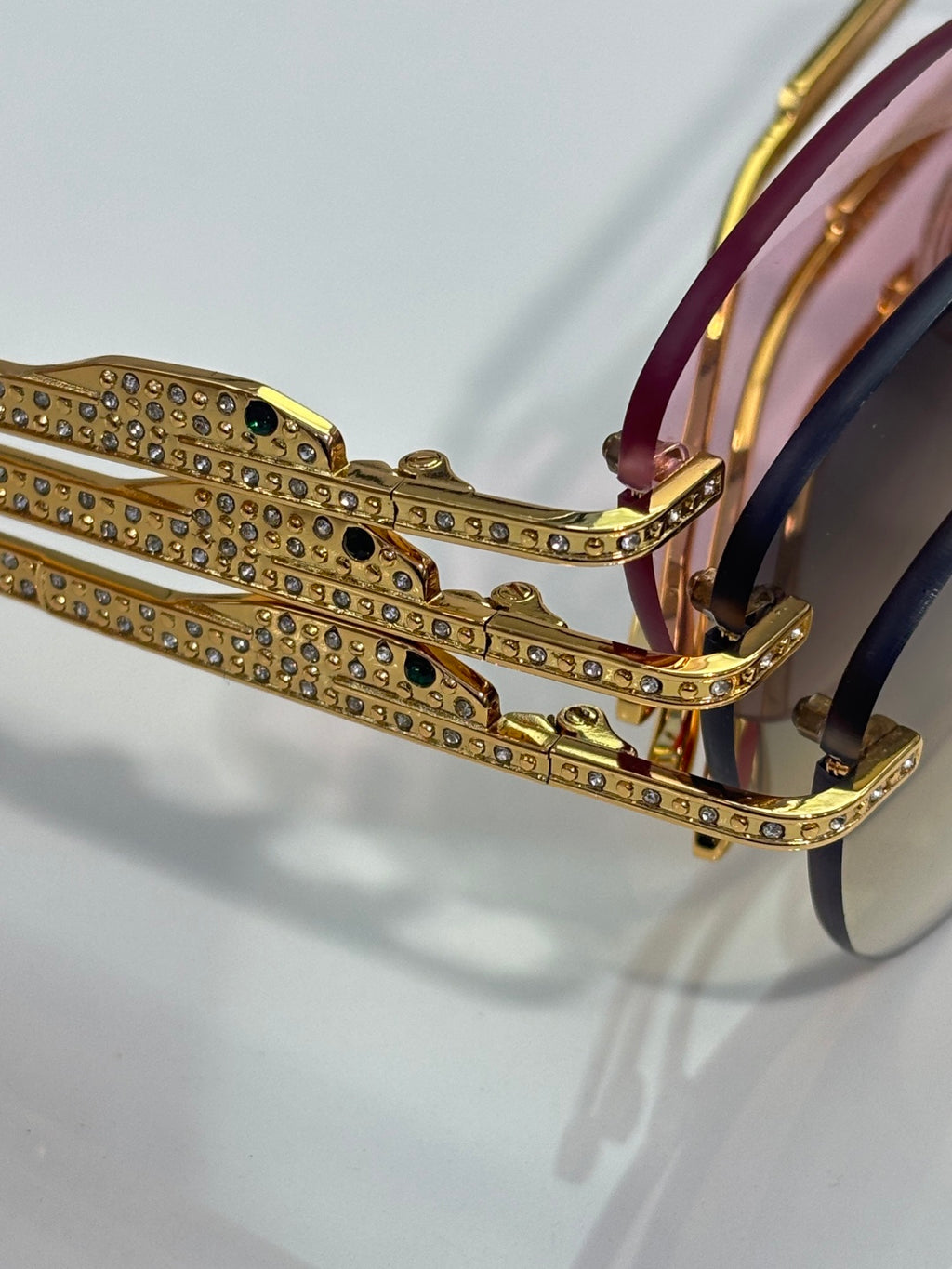 Gold-tone sunglasses closeup with jeweled temple band and tinted lens edge
