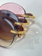 Gold-tone sunglasses closeup with jeweled temple details and tinted lenses