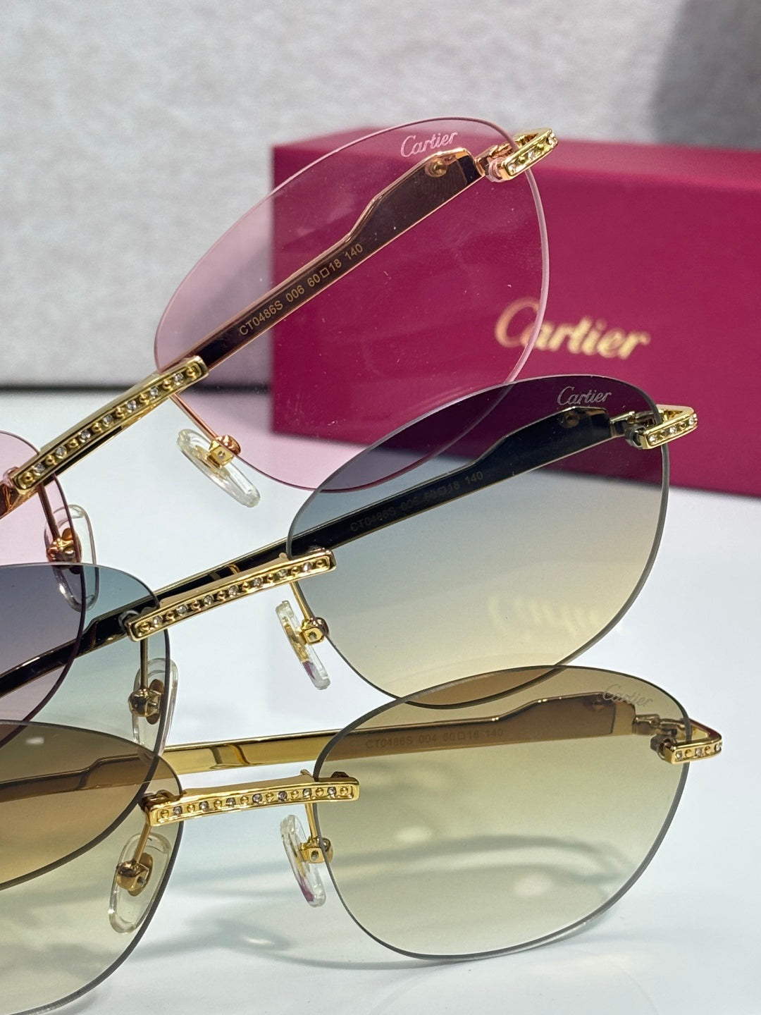 Two gold-tone jeweled sunglasses with tinted lenses, shown from side angles