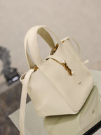 YSL bag in cream leather with gold hardware, adjustable crossbody strap and rounded top profile.