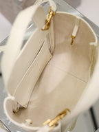 YSL bag interior view in cream leather with stitched lining and gold top clasp hardware visible.
