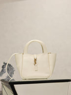 YSL bag in cream leather with gold clasp and top handles, structured mini silhouette.