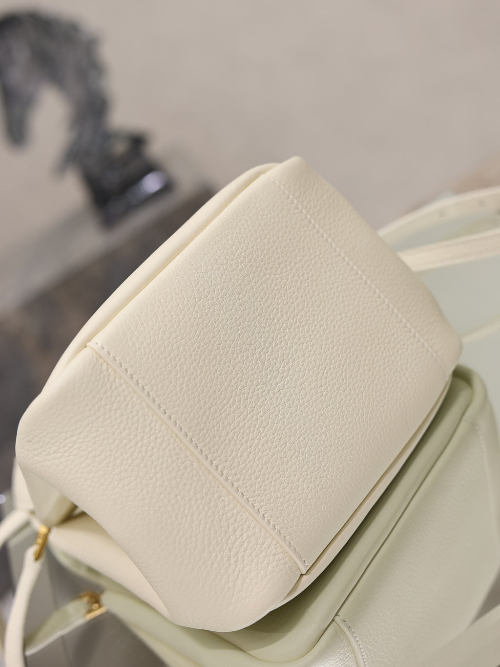 YSL bag in cream leather with padded back panel seam and compact top profile, close-up.