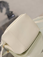 YSL bag in cream leather with padded back panel seam and compact top profile, close-up.
