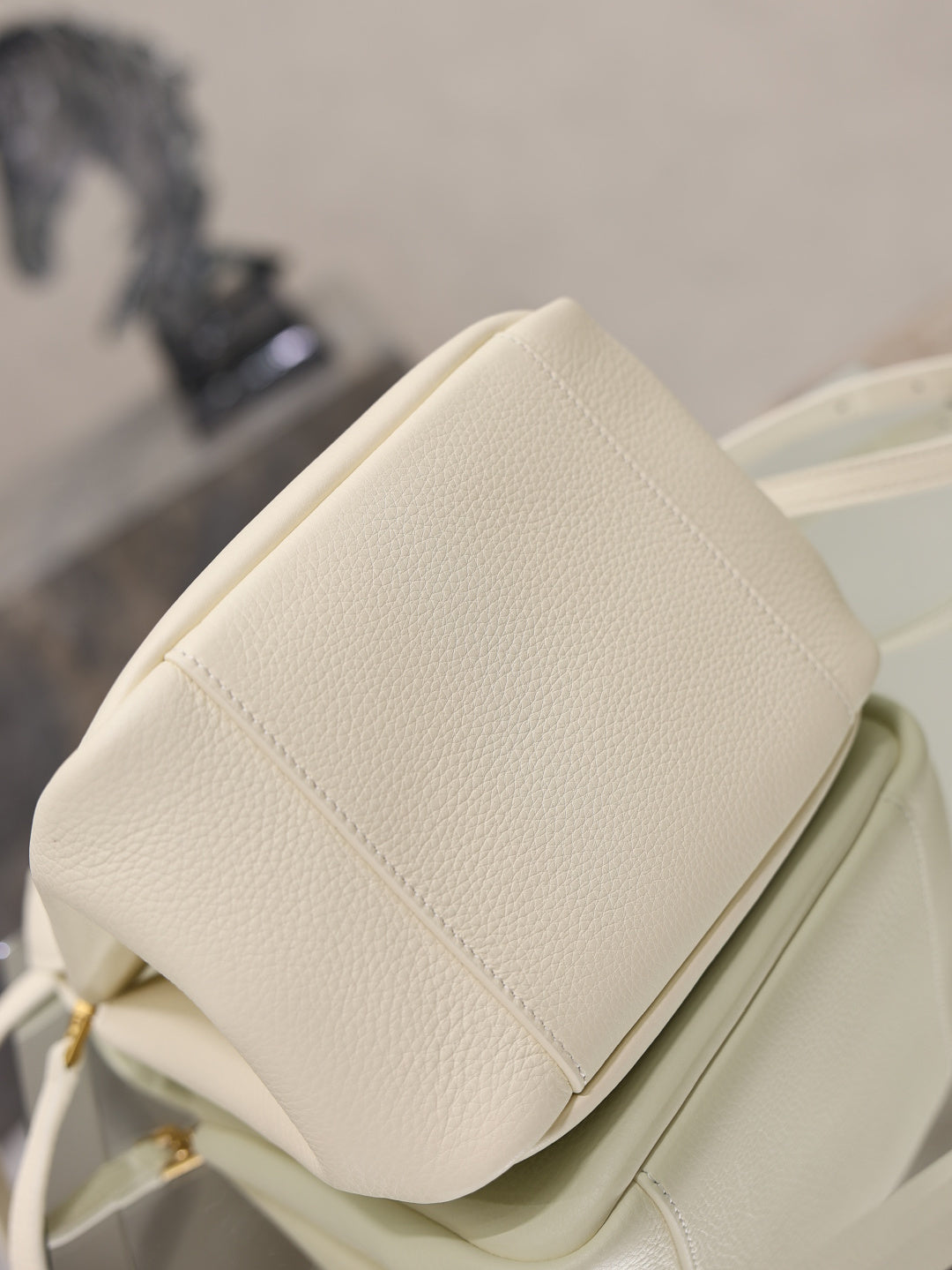 YSL bag in cream leather with padded back panel seam and compact top profile, close-up.