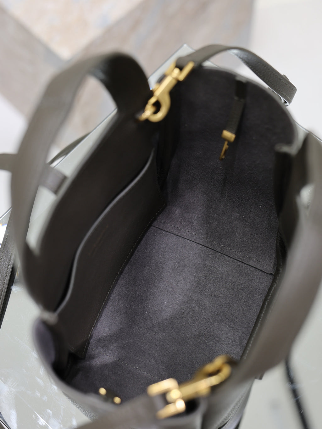 YSL dark leather bag opening view with gold-tone YSL charm and interior lining
