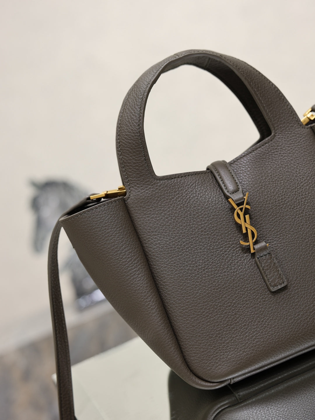 YSL dark leather mini bag with YSL monogram clasp, short handle, and shoulder strap