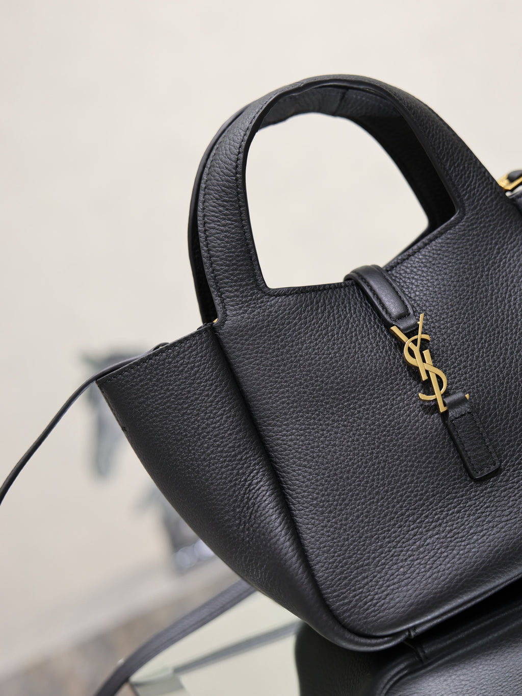 YSL black leather mini tote bag close-up with top handle and gold logo detail