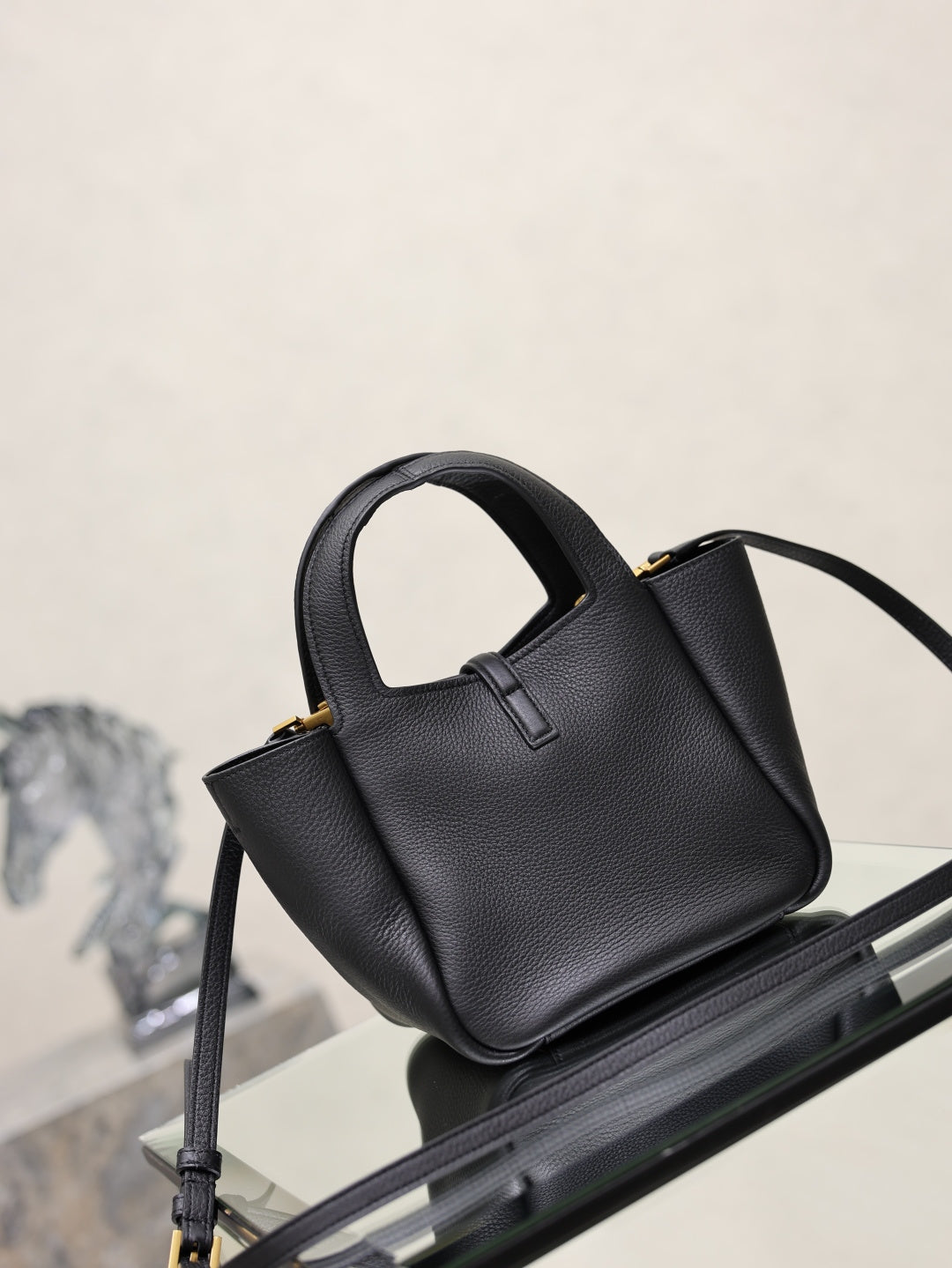 YSL black leather mini tote bag angled view with shoulder strap and gold logo plaque