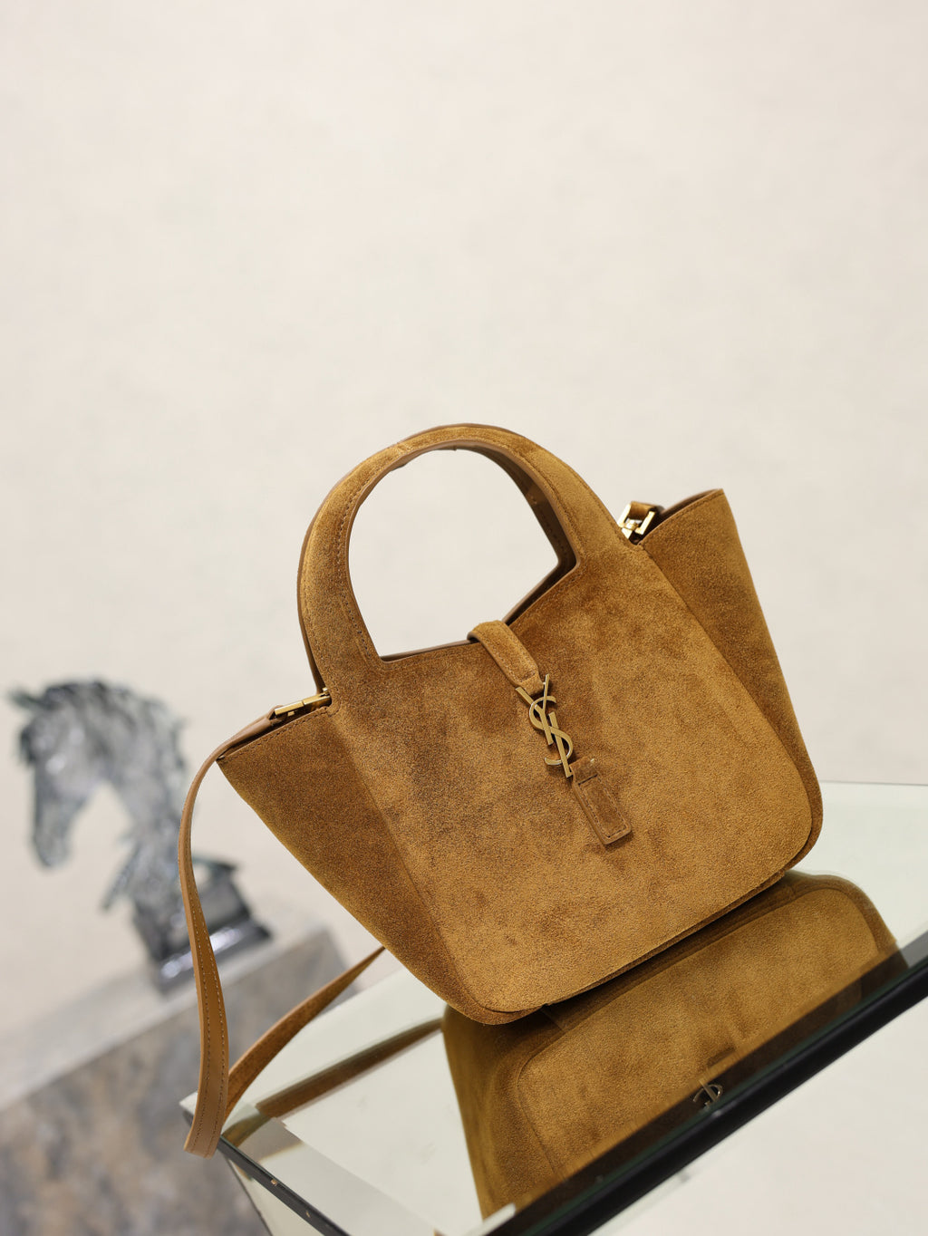 Tan suede mini tote bag with YSL logo charm and shoulder strap, angled view.