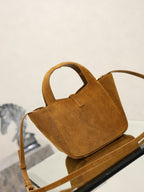 Tan suede mini tote bag with short top handle and YSL logo charm.