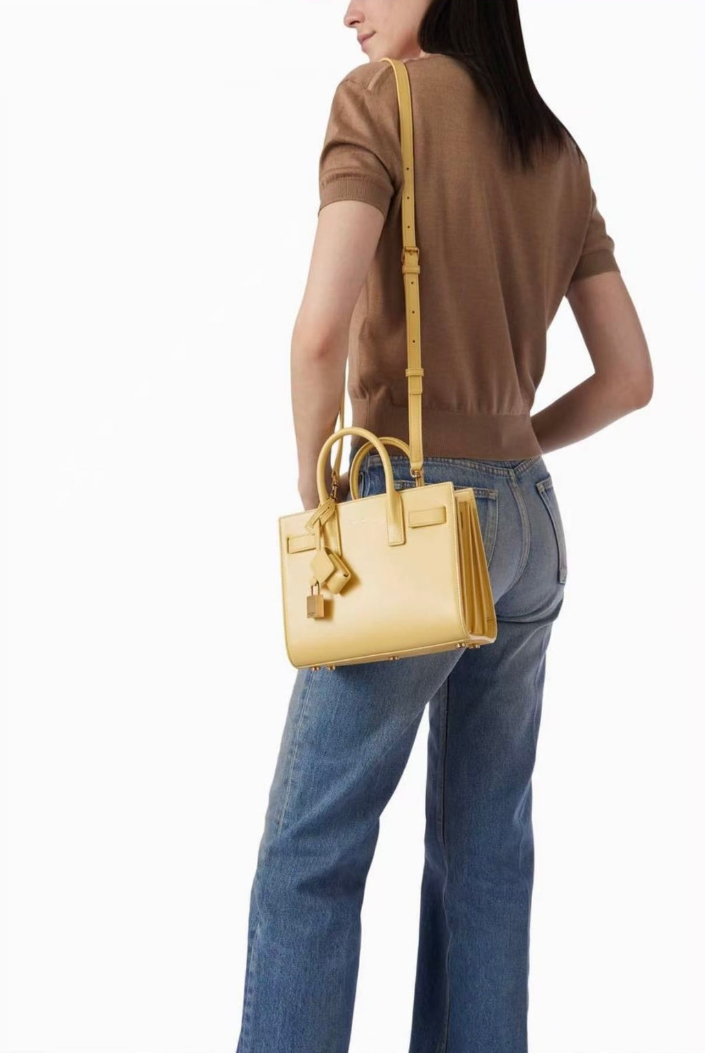 Light yellow tote bag with long crossbody strap worn with jeans and brown top