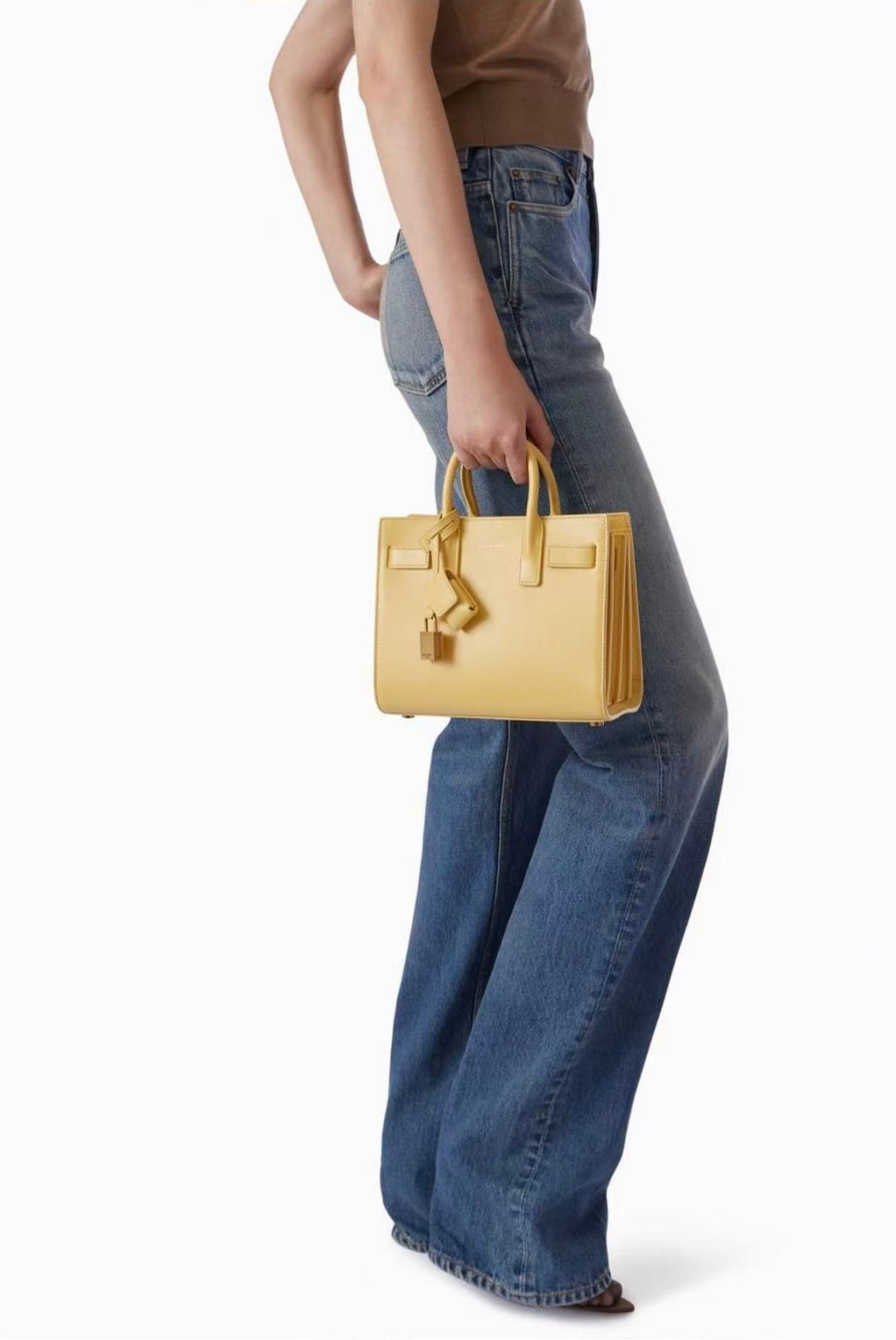 Light yellow tote bag with top handles held by model in blue jeans