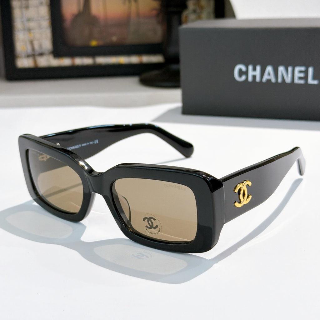 Chanel cat-eye glasses with dark frames and gold CC temple logo; tinted lenses.