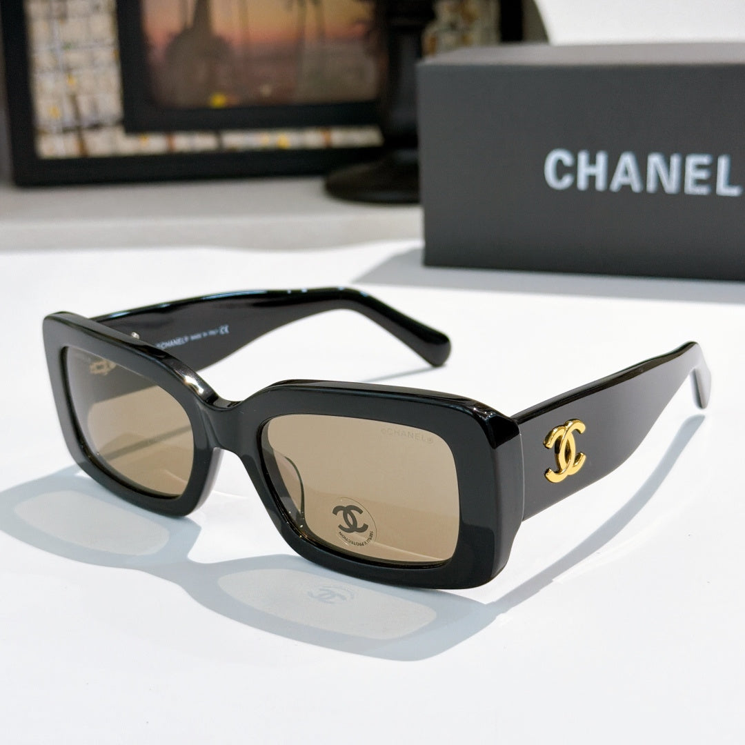 Chanel cat-eye glasses with dark frames and gold CC temple logo; tinted lenses.