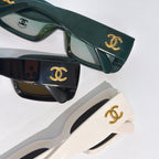 Chanel cat-eye glasses close-up: dark green, black, and white frames with gold CC.