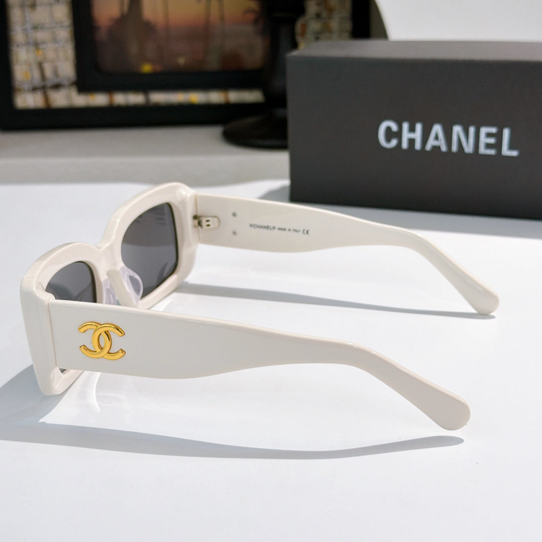 Chanel cat-eye glasses with white frames and gold CC logo on the temple.