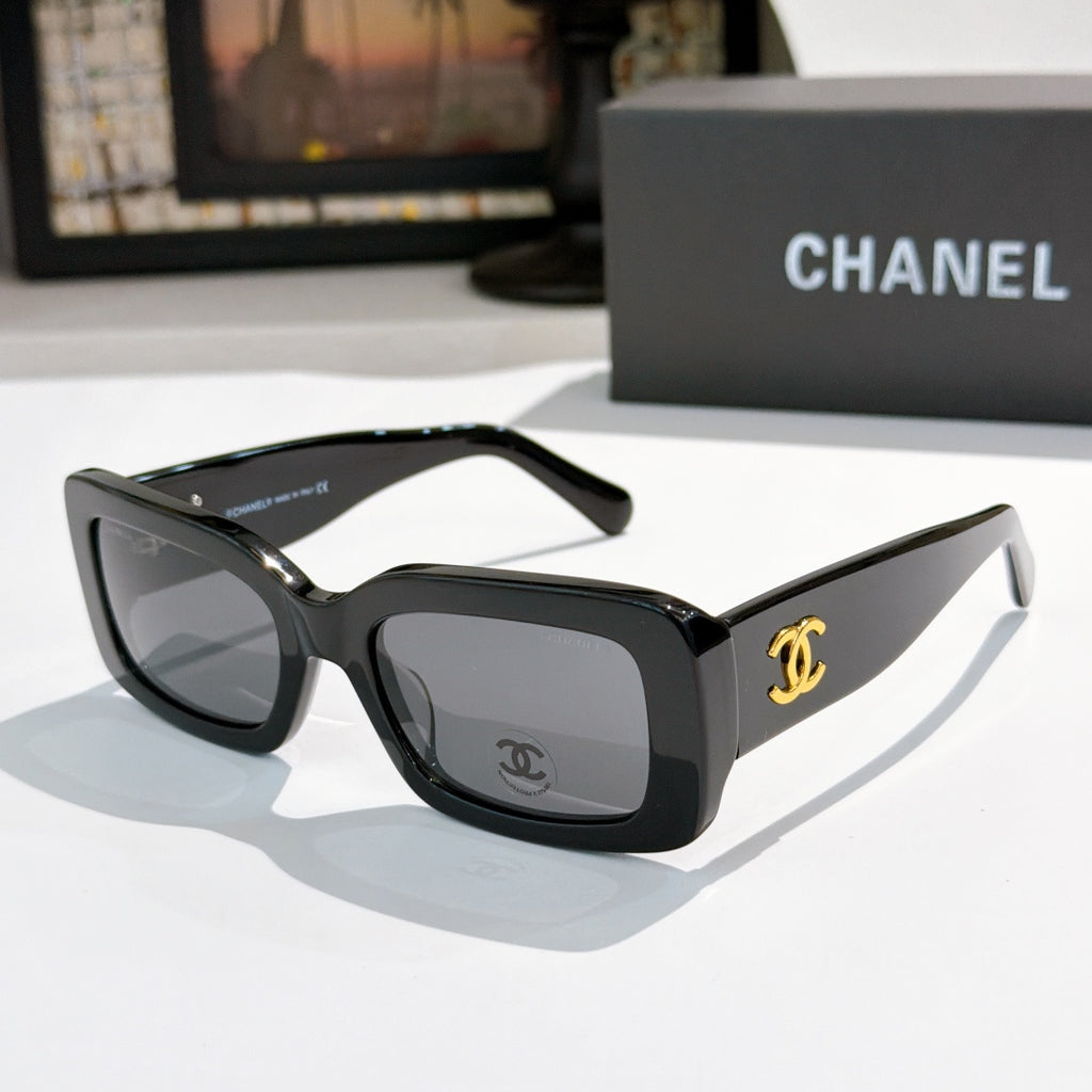 Chanel cat-eye glasses with black frames, tinted lenses, and gold CC temple logo.