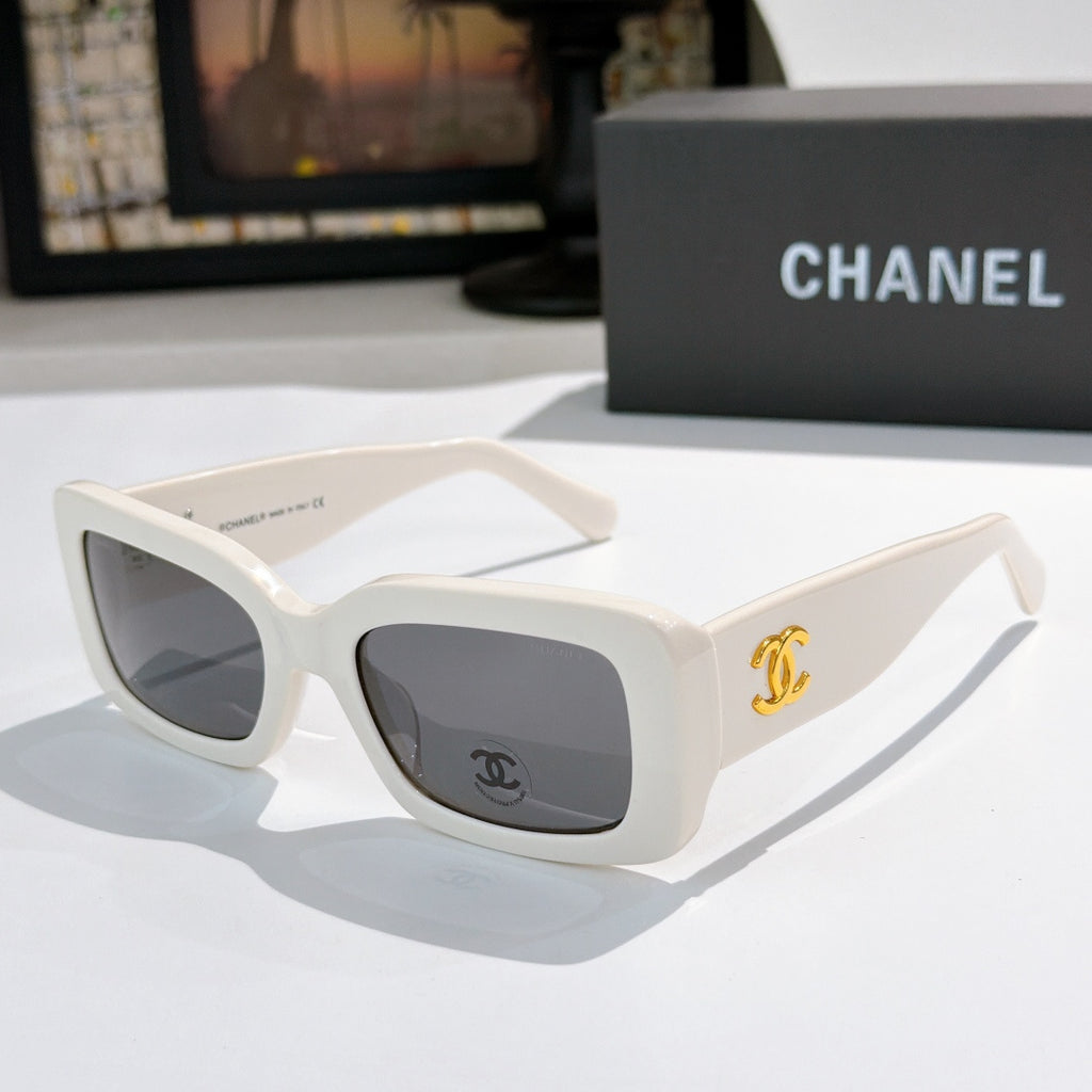 Chanel cat-eye glasses with white frames and gold CC logo at the temple.