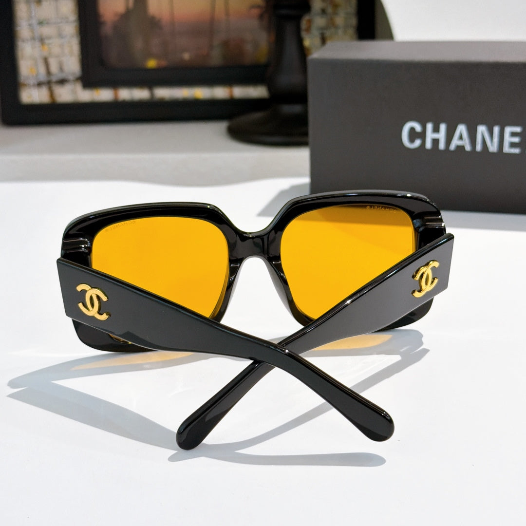 Black square sunglasses with bright yellow tinted lenses and gold CC logo.