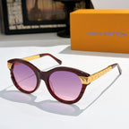 Round dark red sunglasses with purple-tinted lenses and gold logo temple arms