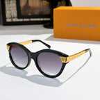 Round black sunglasses with dark purple-tinted lenses and gold logo temple arms