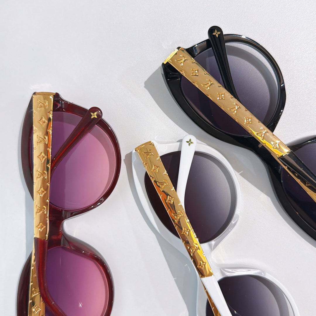 Pair of oval sunglasses with gold logo temples, one black and one burgundy, purple lenses