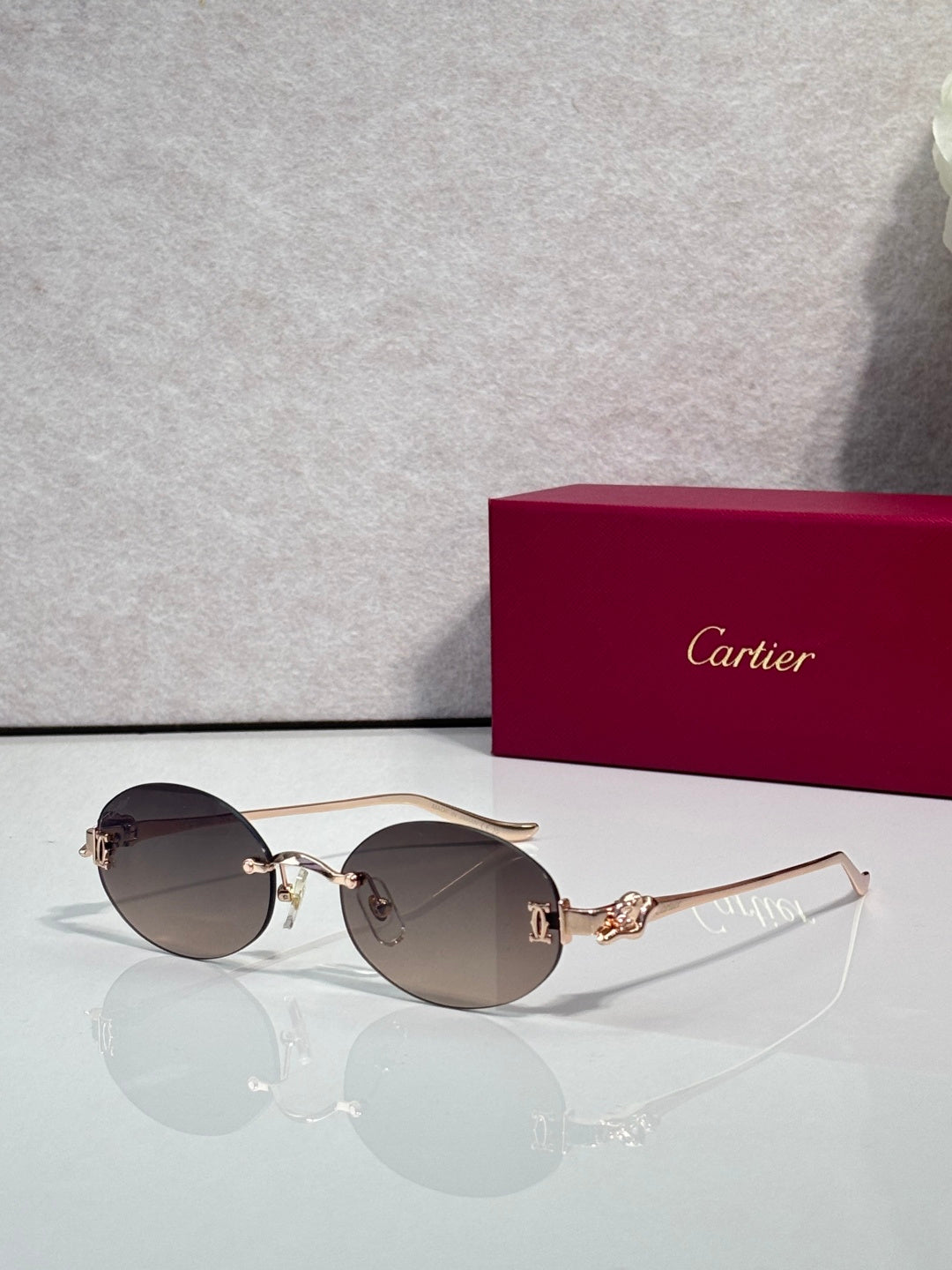 Round brown-tinted sunglasses with gold-tone metal frames and decorative hinge detail