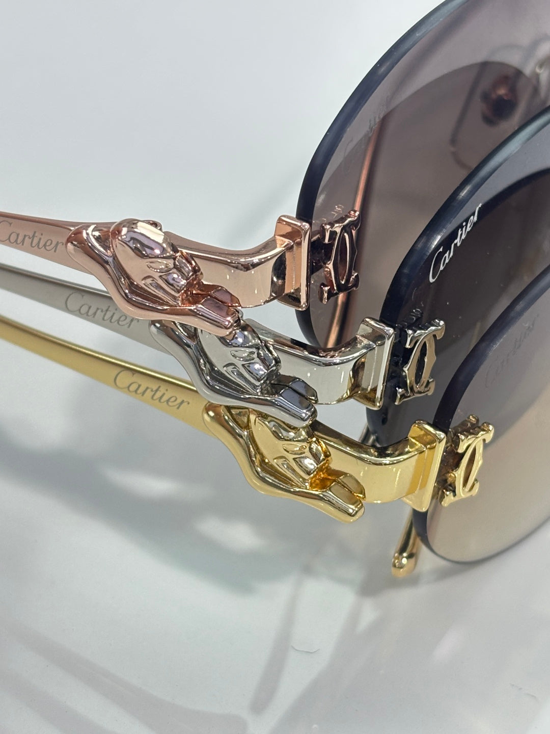 Close-up of gold-tone sunglasses hinges with stacked metal links and dark lenses