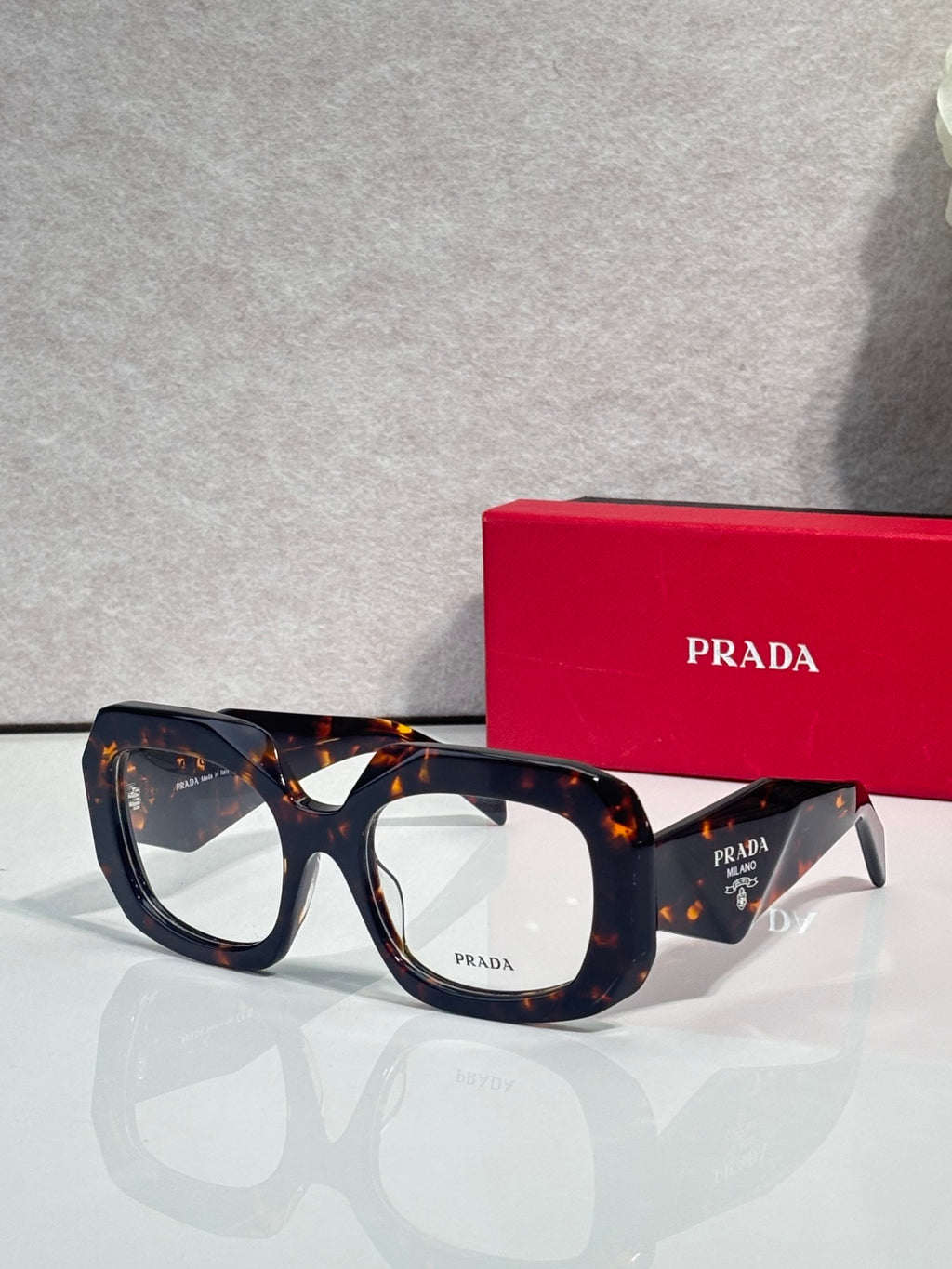 Prada eyeglasses with dark blue frames and clear lenses, tortoise-pattern temples