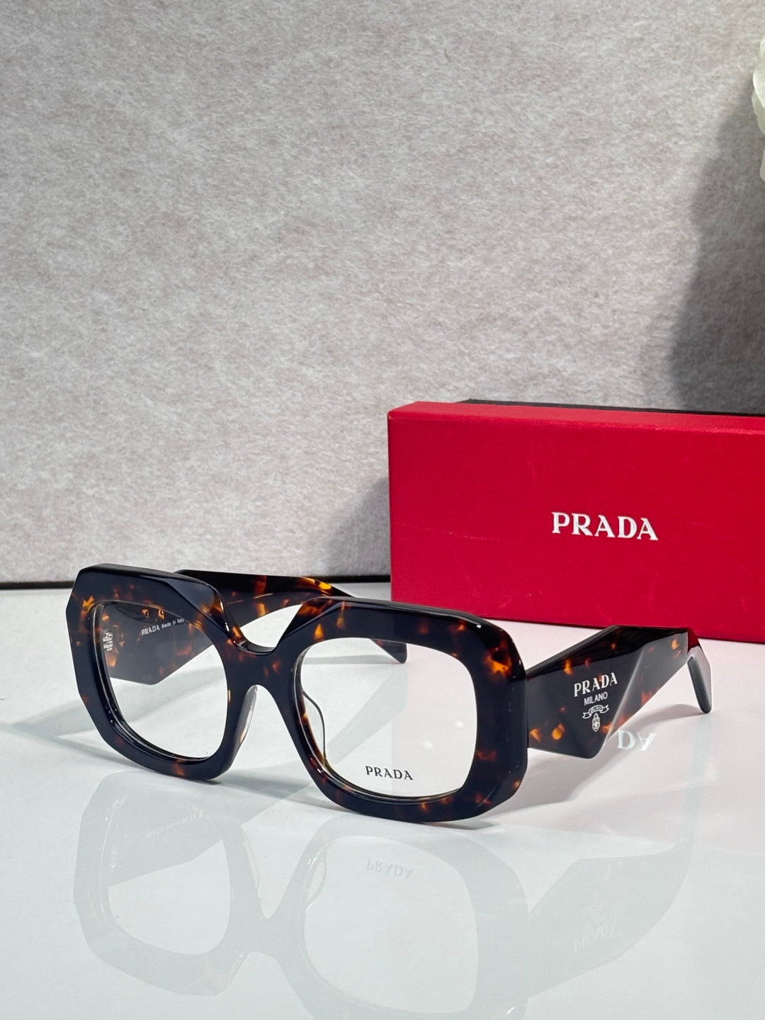 Prada eyeglasses with dark blue frames and clear lenses, tortoise-pattern temples
