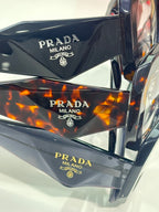 Prada eyeglasses temple close-up with PRADA MILANO branding on dark frames