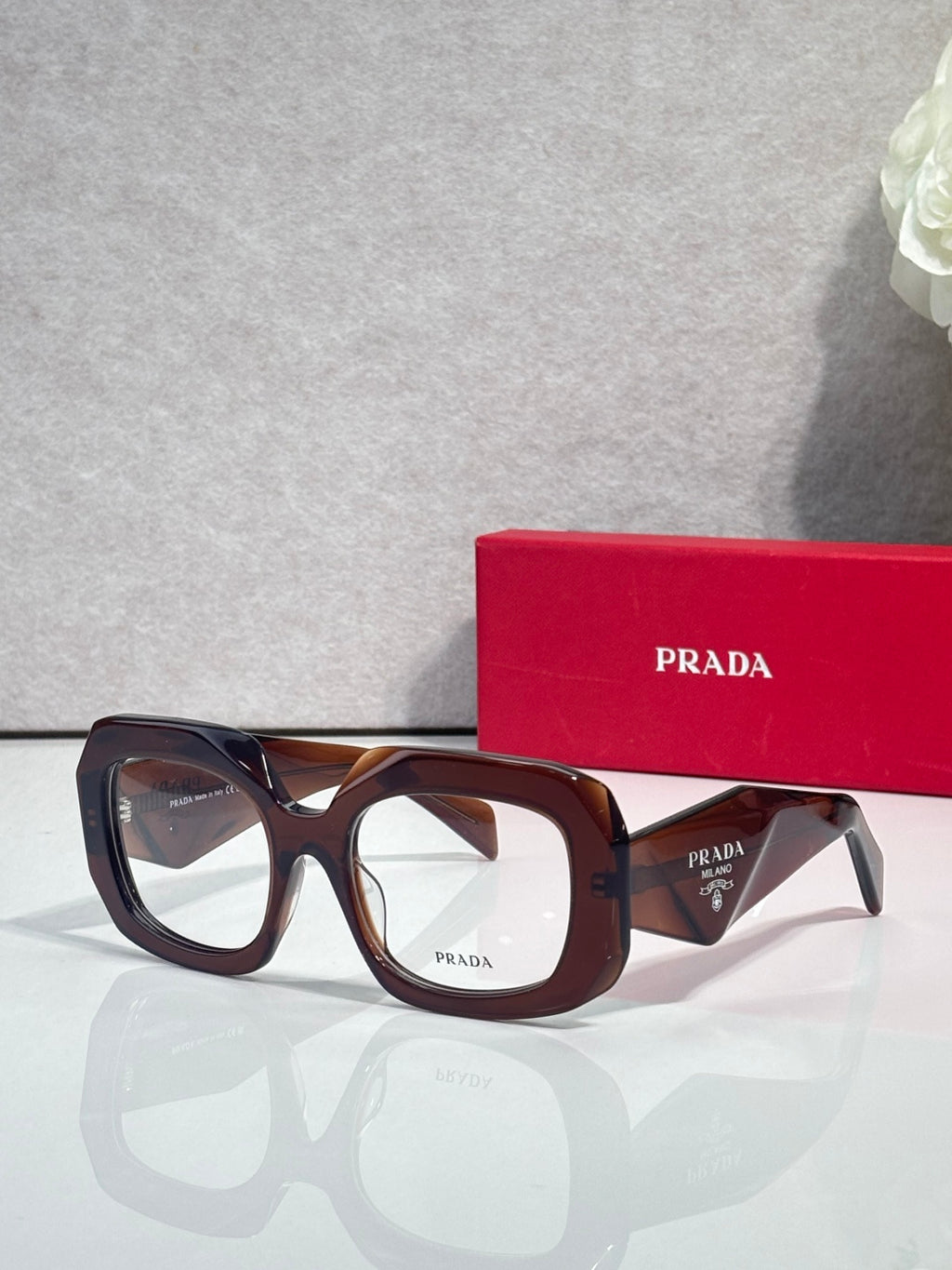 Prada eyeglasses with dark brown frames and clear lenses, tortoise-pattern temples