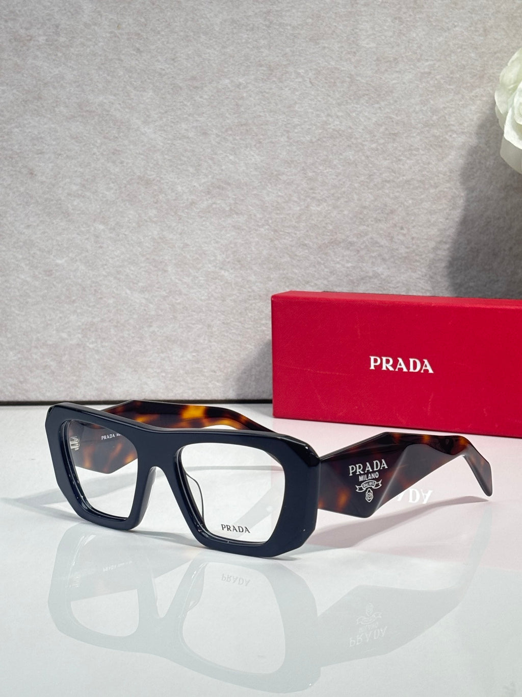 Prada black rectangular eyeglasses with clear lenses and tortoise top edge