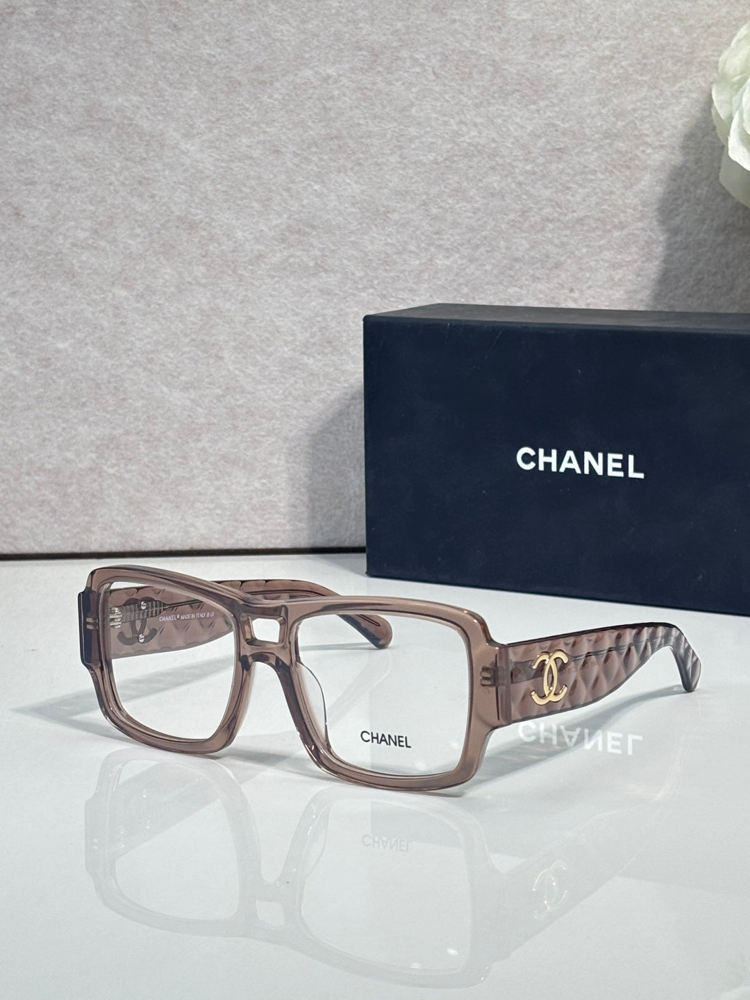Brown rectangular eyeglasses with CHANEL logo and patterned temple arms