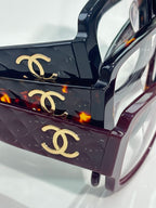 Close-up of patterned dark purple eyeglasses with gold CC logos on the top bar
