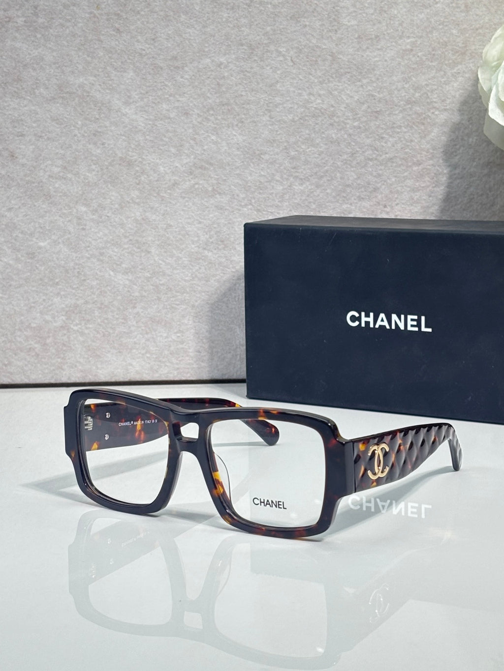 Tortoiseshell and black rectangular eyeglasses with CHANEL logo and patterned temple arms