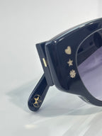 Sunglasses close-up: dark blue temple with gold star and heart motifs