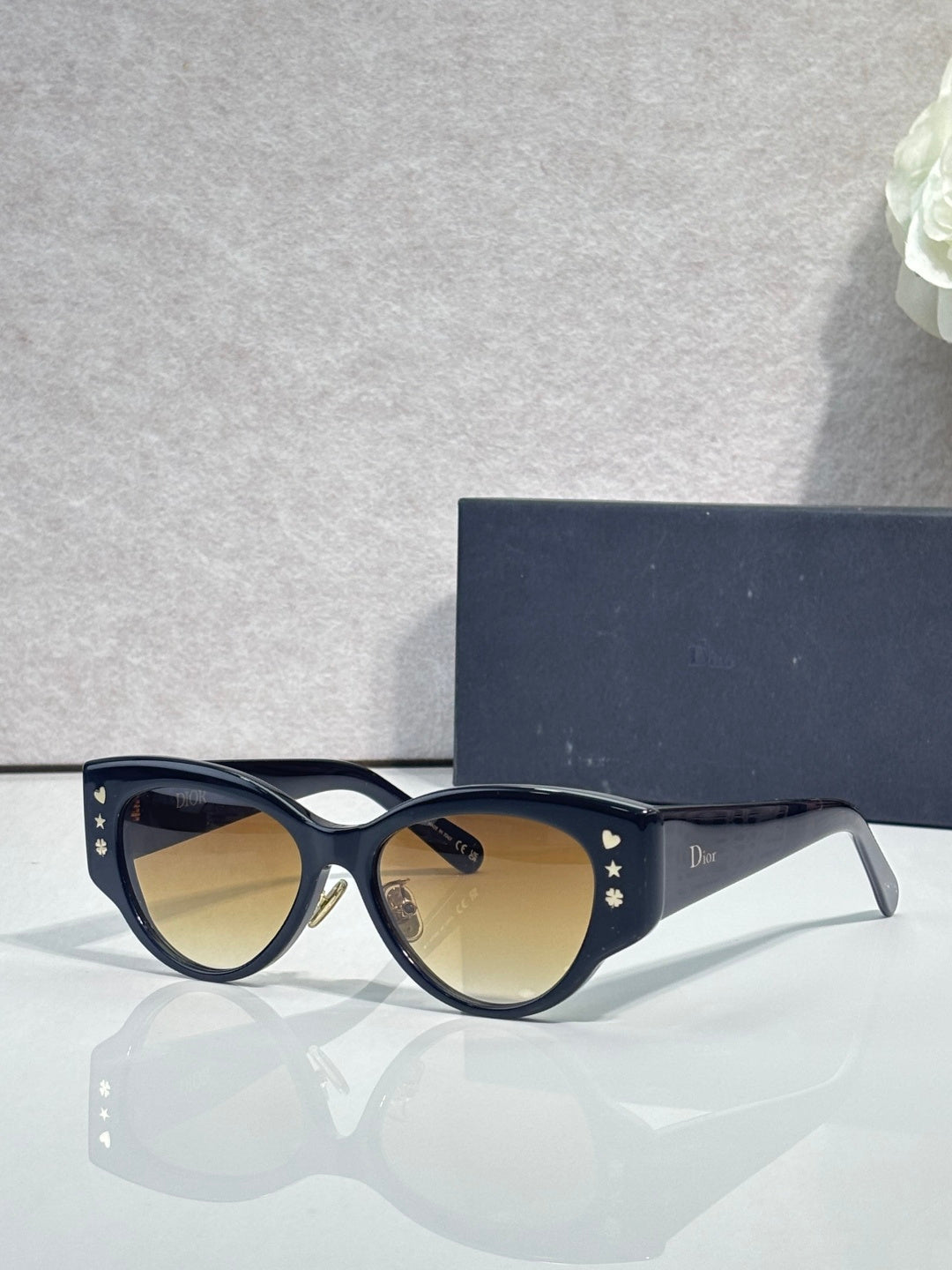 Sunglasses with dark blue cat-eye frames, gold star accents, and amber-tinted lenses