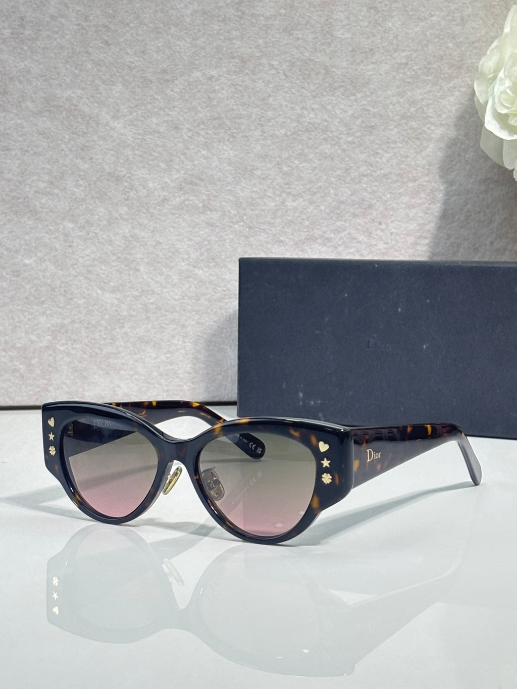 Sunglasses with dark blue frames, gold star accents, and gradient tinted lenses