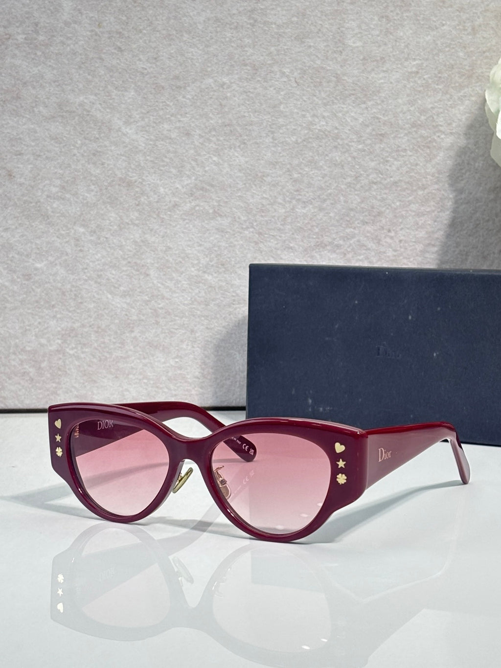 Sunglasses with burgundy frames, gold star accents, and rose-tinted lenses
