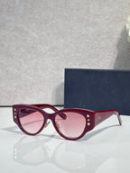 Sunglasses with burgundy frames, gold star accents, and rose-tinted lenses