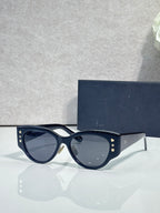 Sunglasses with navy cat-eye frames, gold star detailing, and tinted lenses