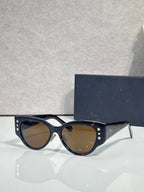 Sunglasses with dark blue cat-eye frames, gold star accents, and tinted lenses